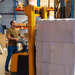Een medewerker van Euralpack met een stapelaar tussen de magazijnrekken.