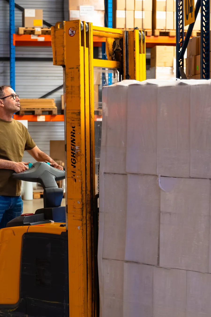 Een medewerker van Euralpack met een stapelaar tussen de magazijnrekken.