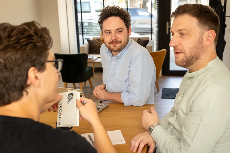 Drie Barabas-collega's in gesprek rond de tafel op kantoor