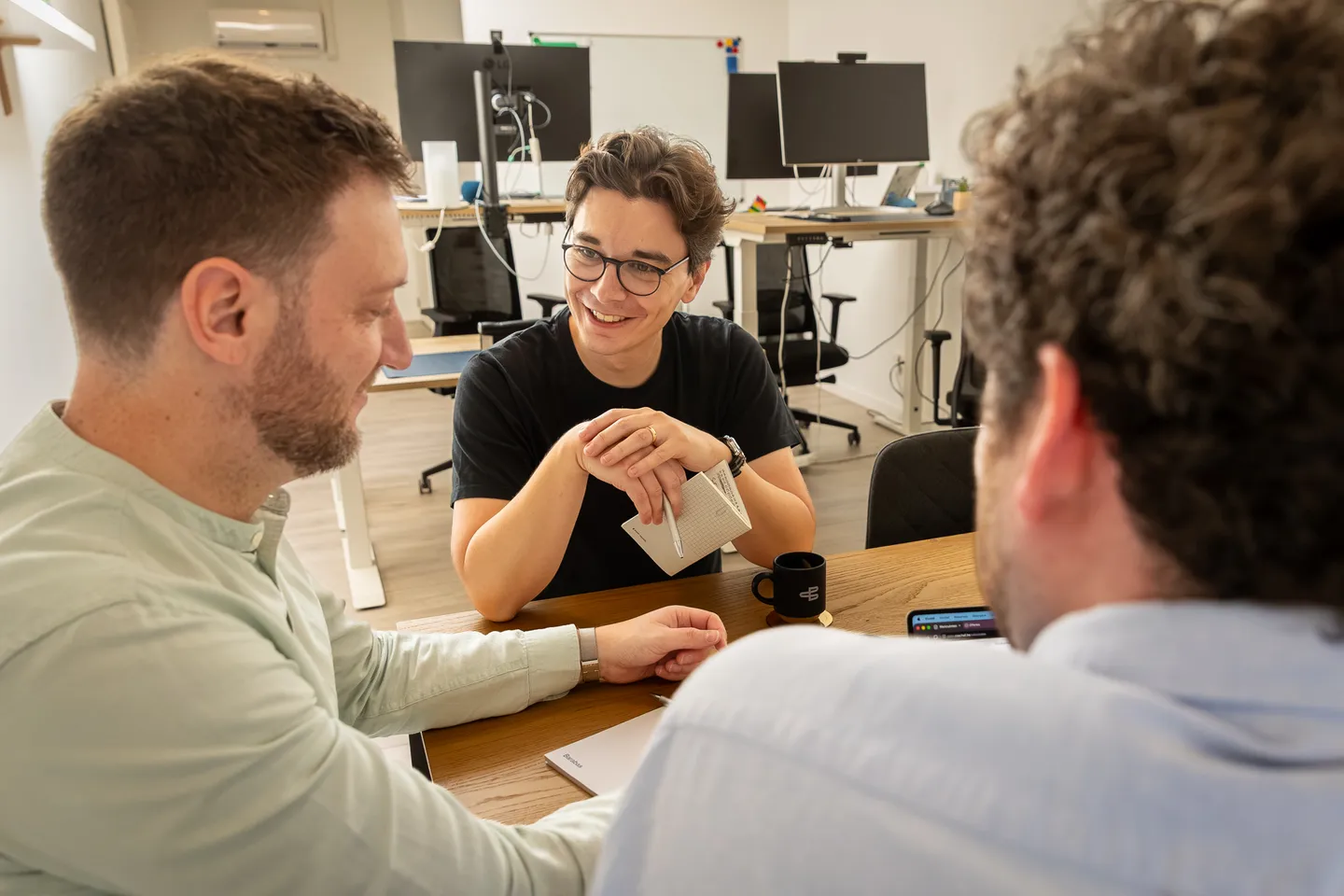 Drie Barabas-collega's in gesprek rond de tafel op kantoor