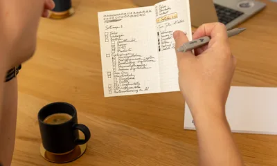 Handgeschreven checklist wordt afgevinkt aan de vergadertafel