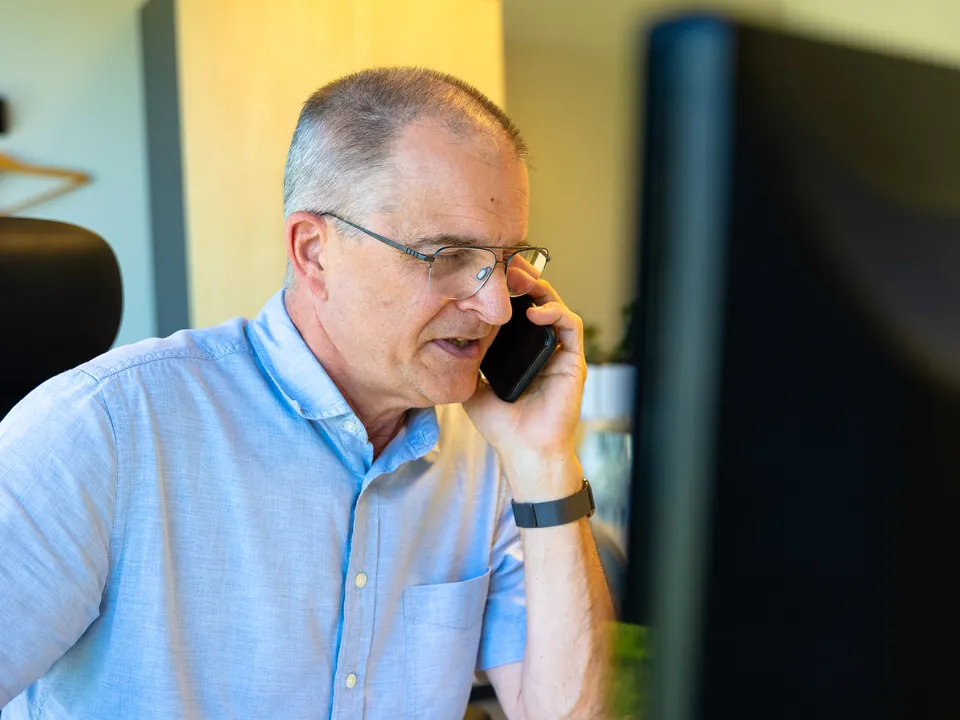 Zaakvoerder aan de telefoon achter zijn bureau