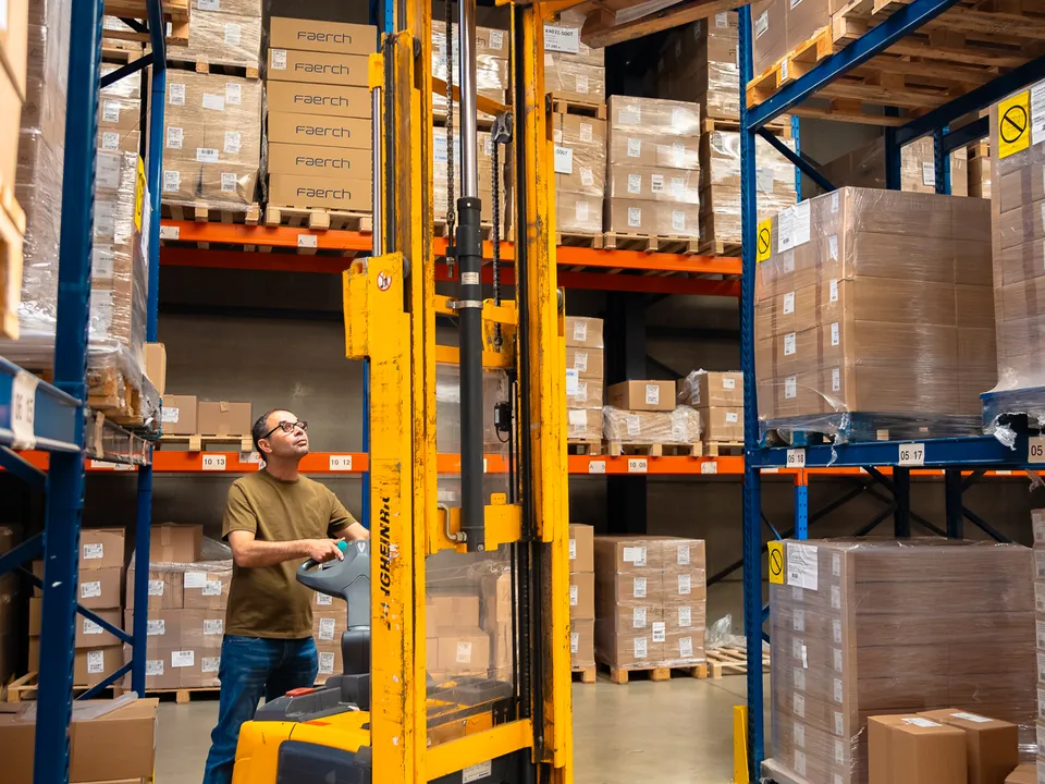 Magazijnier zet met een stapelaar een pallet in het hoogste rek