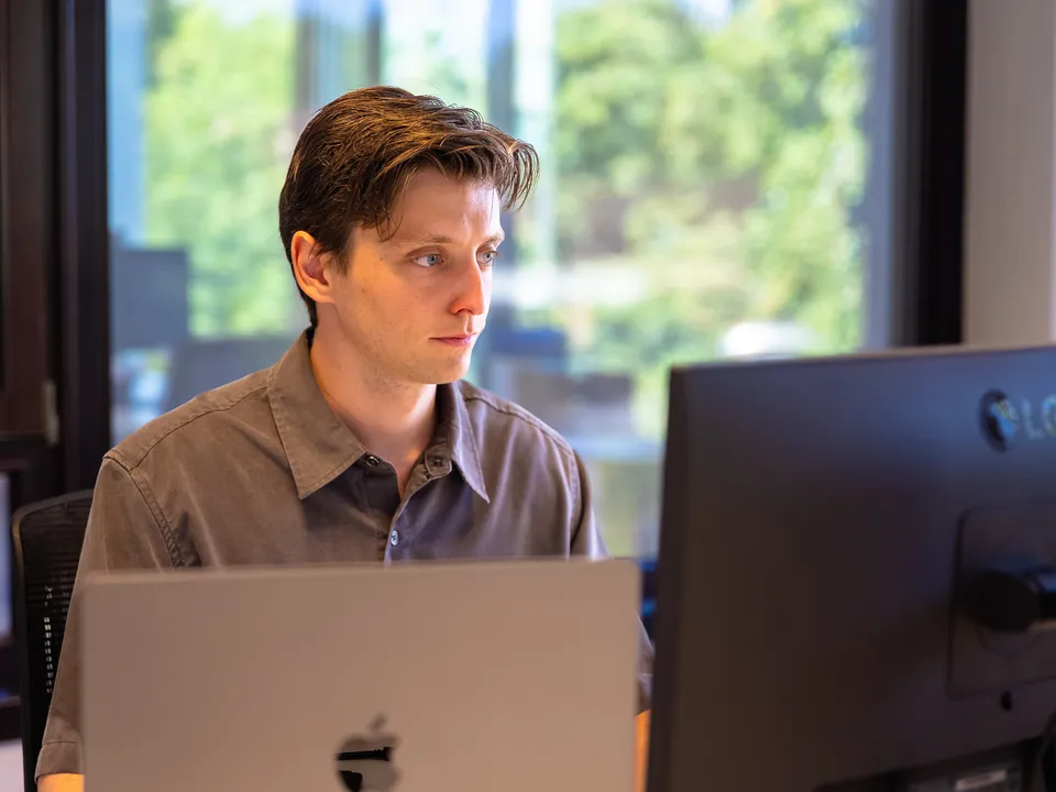 Medewerker aan het werk achter laptop en scherm bij het raam
