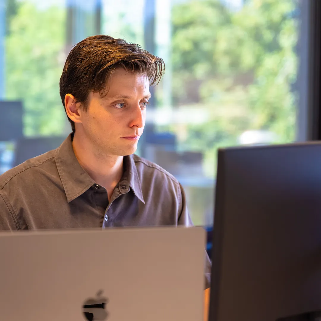 Medewerker aan het werk achter laptop en scherm bij het raam