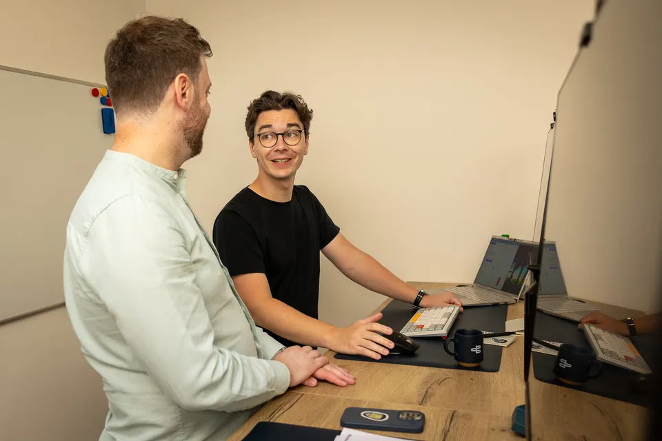 Twee Barabas-collega's overleggen aan een bureau terwijl ze aan software werken